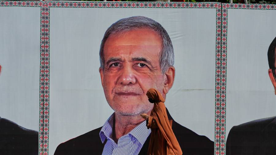 Una mujer pasa frente a un anuncio con la imagen del presidente de Irán, Masoud Pezeshkian, en Islamabad, Pakistán.