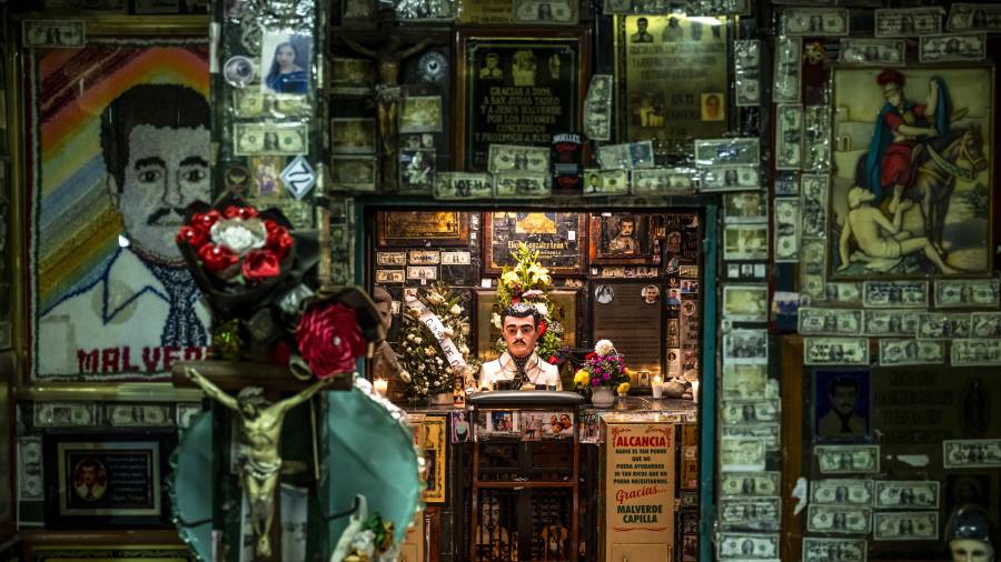 Ofrendas de flores, velas, fotos y billetes de dólar en un santuario dedicado a Jesús Malverde, un “narcosanto”, en Culiacán.