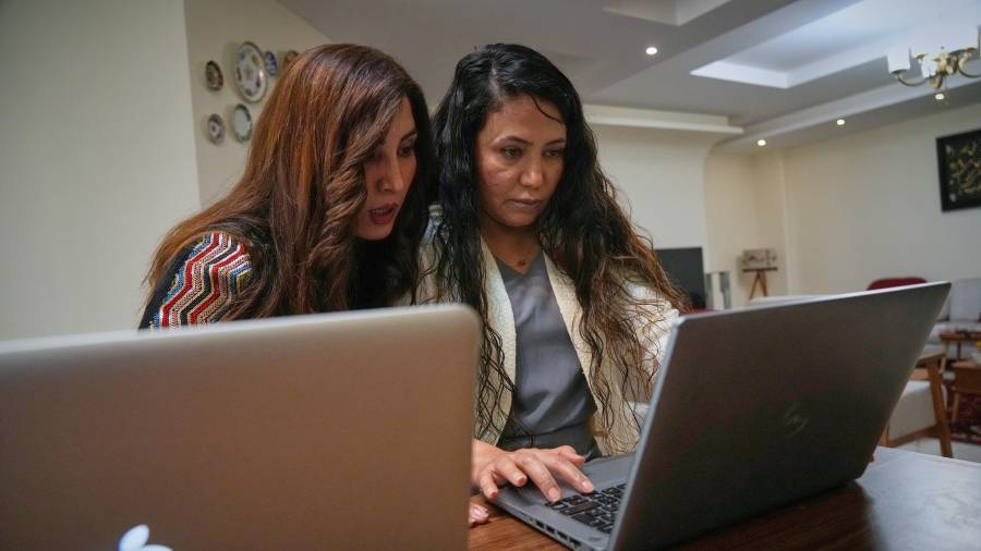 La diseñadora de moda Amen Khademi trabaja en su computadora portátil con la modelo Farnaz Ojaghloo (izquierda) en su estudio en Teherán, Irán
