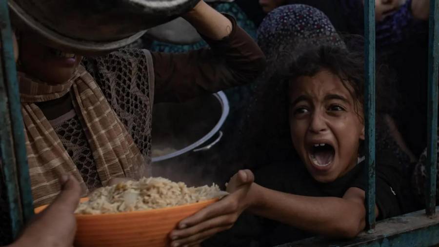 Niños palestinos desplazados internos intentan recoger alimentos donados por un grupo caritativo, en el campamento de Khan Yunis, en el sur de la Franja de Gaza.