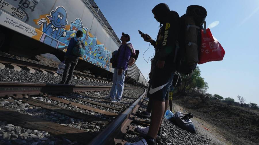 Migrantes miran un tren pasar mientras esperan en las vías con la esperanza de poder abordar uno que vaya hacia el norte, uno que se detenga el tiempo suficiente para que se puedan subir, en Huehuetoca, México.