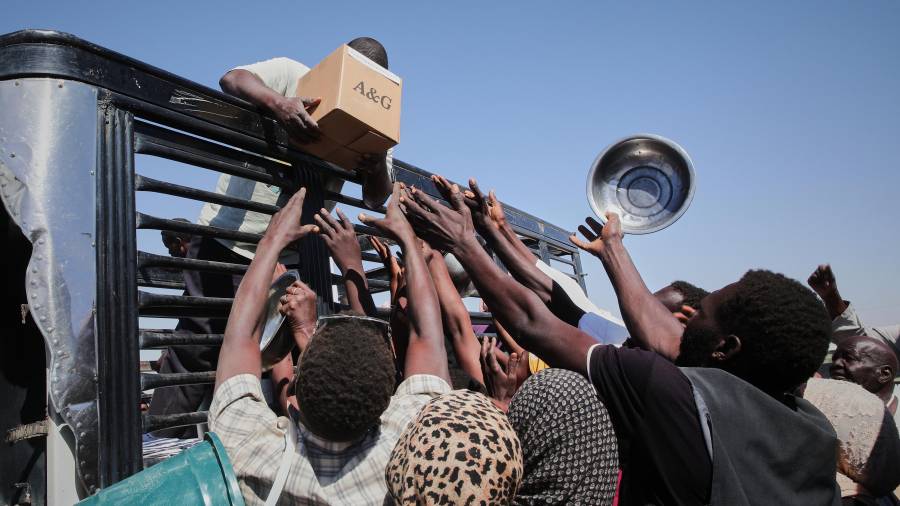 Familias sudanesas desplazadas de El-Fasher se acercan a trabajadores humanitarios que distribuyen alimentos en el campamento de El-Afadh en Al Dabbah, estado norteño de Sudán.