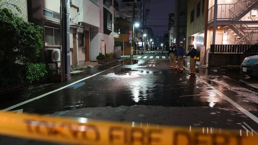 Rescatistas del Departamento de Bomberos de Tokio junto a un camino parcialmente inundado, la madrugada del domingo.