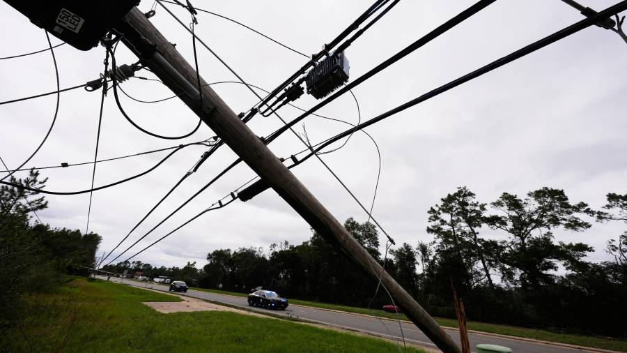 Agentes de la Policía Estatal pasan junto a líneas eléctricas derribadas tras el paso del huracán Isaias en Milton, Florida, el sábado 10 de octubre de 2026.