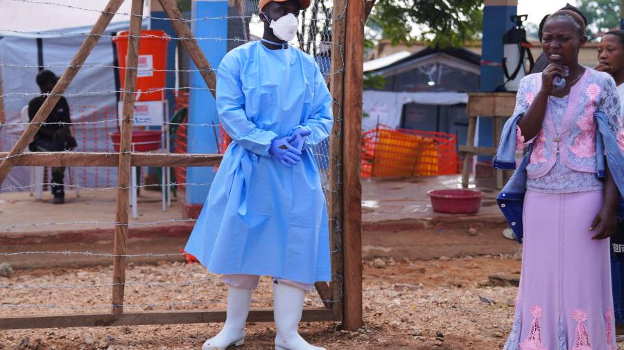 Residentes miran mientras trabajadores de la salud trasladan un ataúd con los restos mortales de una víctima de ébola, en el Centro de Tratamiento de Ébola del Hospital General de Bunia.