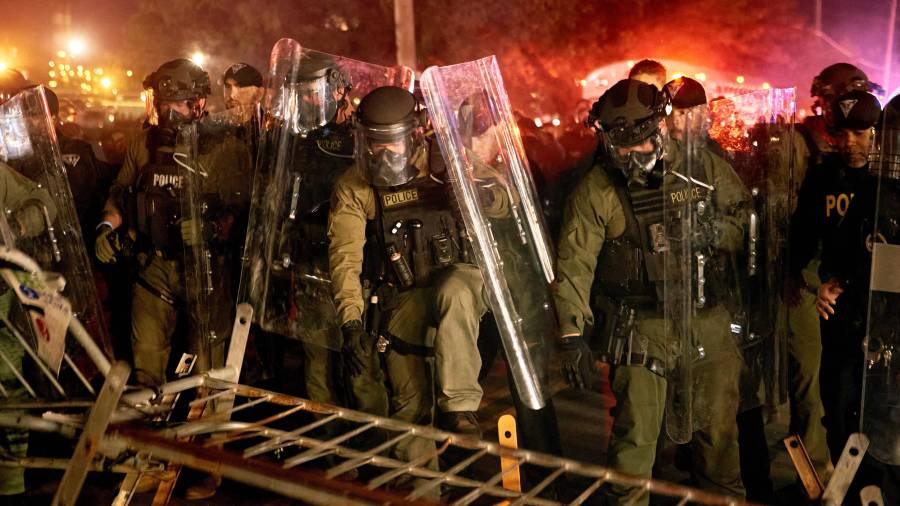 Policías derriban una barricada durante un enfrentamiento con manifestantes cerca del centro de detención Delaney Hall, durante una protesta contra el traslado de detenidos y las políticas federales de inmigración.
