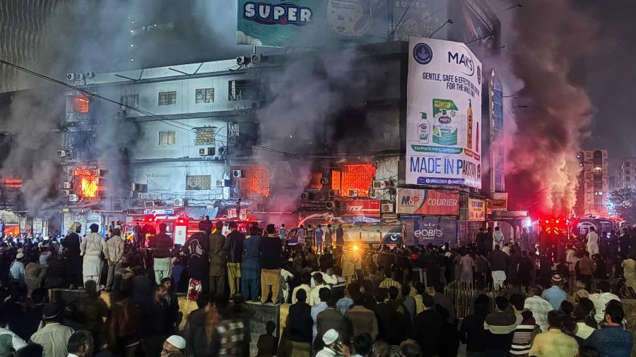 Gente reunida mientras los bomberos intentan conrolar un enorme incendio en un centro comercial de varias plantas en Karachi, Pakistán. FOTO: