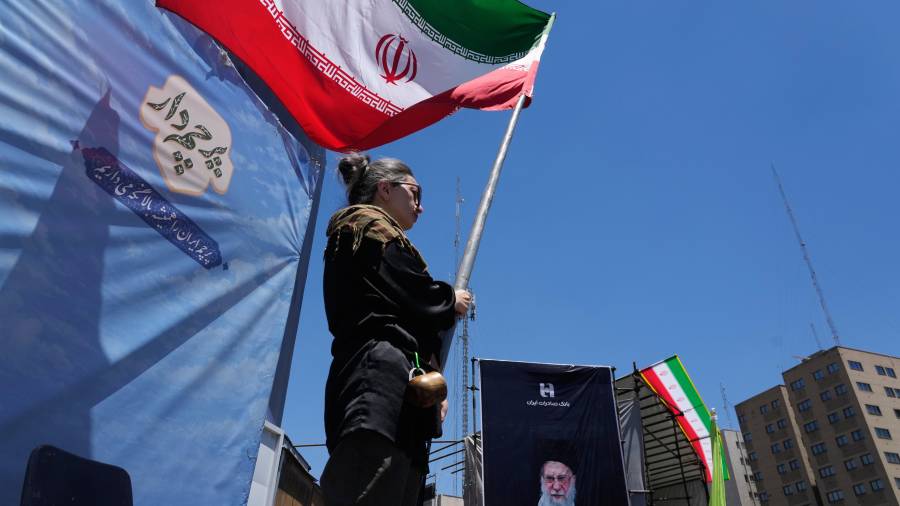 Una mujer ondea una bandera iraní durante una marcha progobierno, donde se ve la imagen del fallecido líder supremo iraní Alí Jamenei, asesinado en ataques de EU e Israel el 28 de febrero.