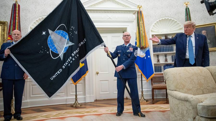 El general John “Jay” Raymond, comandante del Comando Espacial (i), yel suboficial mayor Roger Towberman (c) sostienen la bandera de la Fuerza Espacial junto con Donald Trump en la Casa Blanca.