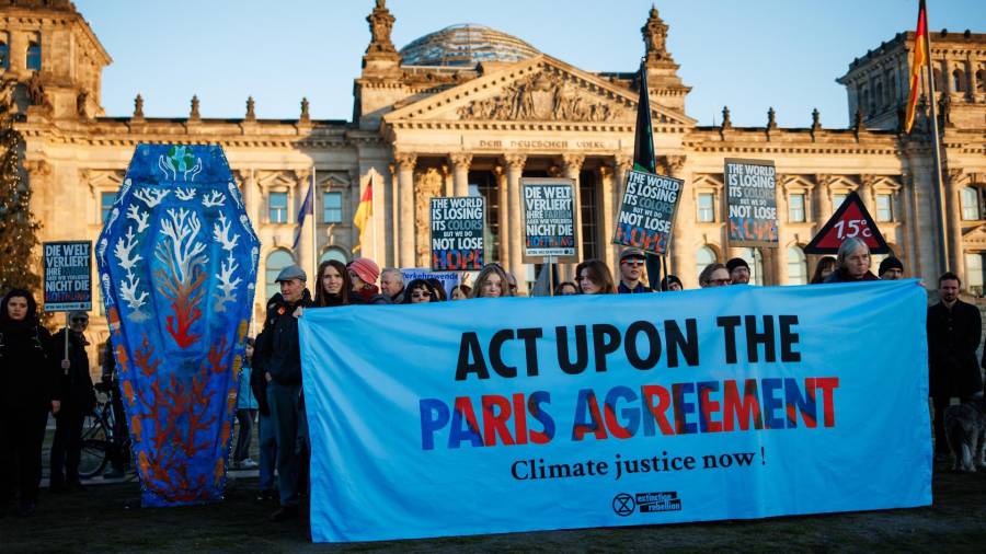 Activistas de Extinction Rebellion protestan con una pancartas que dice ‘Actuar sobre el acuerdo de París’ y un ataúd gigante frente al Parlamento alemán con motivo de los 10 años del Acuerdo de París en Berlín.