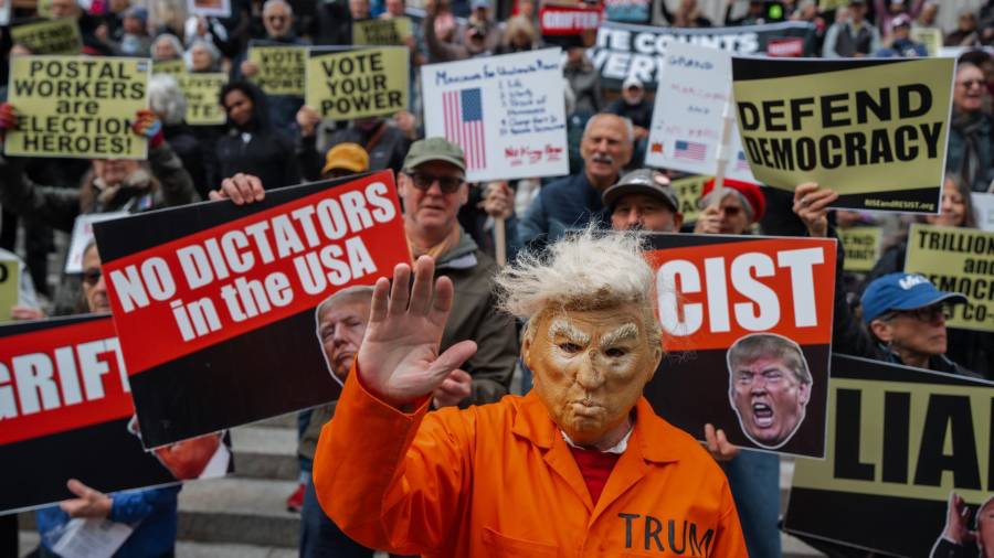 Una persona que lleva una máscara que representa al presidente de EU, Donald Trump, y un uniforme de presidiario de color naranja, participa en una manifestación bajo el lema “No Kings” en Nueva York.