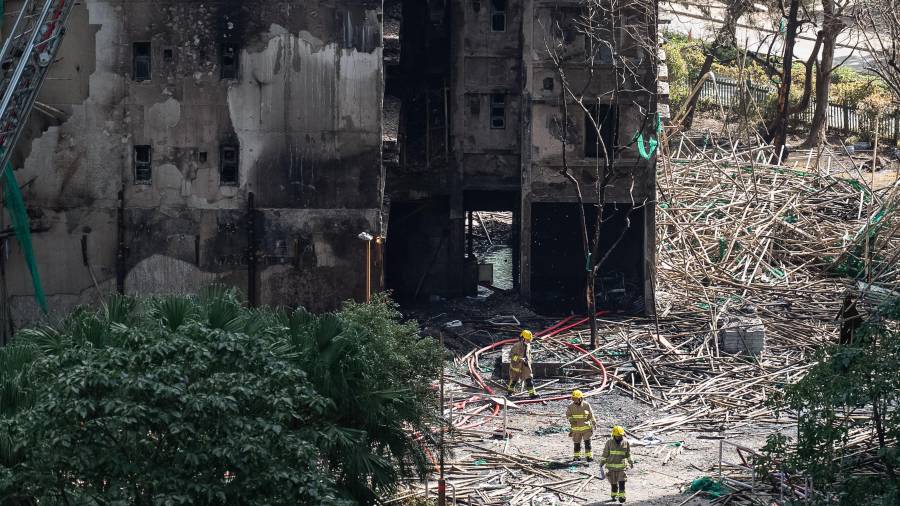 Los bomberos caminan entre los edificios quemados tras el incendio mortal que comenzó el miércoles en Wang Fuk Court, una urbanización en el distrito de Tai Po, en los Nuevos Territorios de Hong Kong.