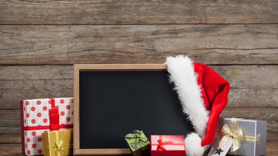 Slate, gift box and santa hat arranged on wooden table during chirtsmas time