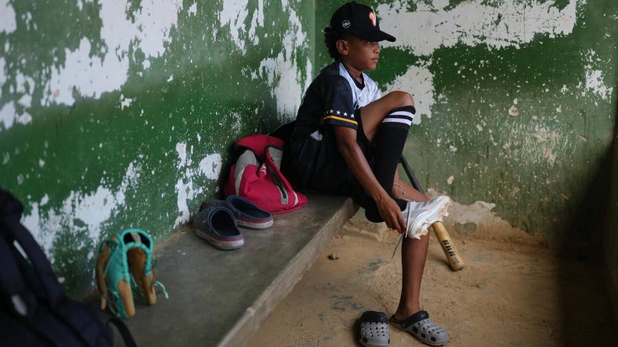 Yeferson Seijas se pone sus zapatos deportivos para un entrenamiento de béisbol en La Guaira, Venezuela; después de que los sismos dejaran a su familia sin hogar.