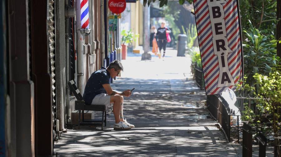 Un joven revisa su celular en una solitaria calle de la alcaldía Cuauhtémoc, Ciudad de México.