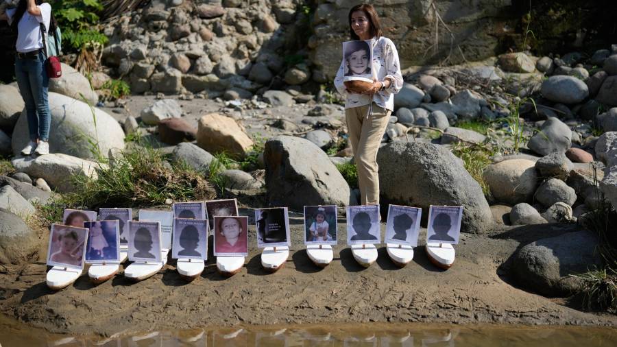 Martha Lucía López sostiene una barca con una foto de su hijo Sergio Melendro López, desaparecido desde la erupción del Nevado del Ruiz, antes de que se lanzaran al río Guali, en Honda, Colombia.