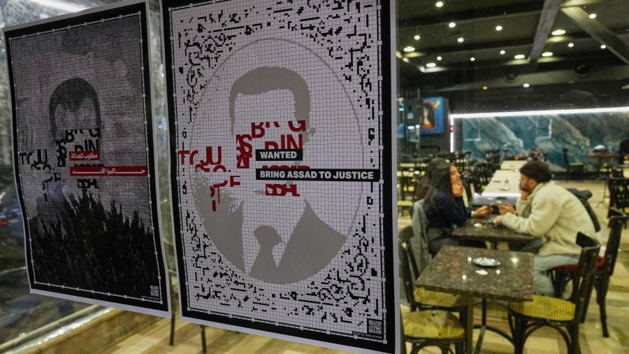 Carteles de “se busca” con la imagen del expresidente sirio Bashar Assad se ven en la ventana de una cafetería en Damasco, mientras los sirios celebran el primer aniversario de la caída del régimen de Assad.