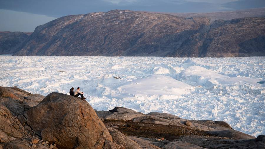 Estudiantes investigadores de la NYU se sientan sobre una roca con vistas al glaciar Helheim, en Groenlandia, el 16 de agosto de 2019.