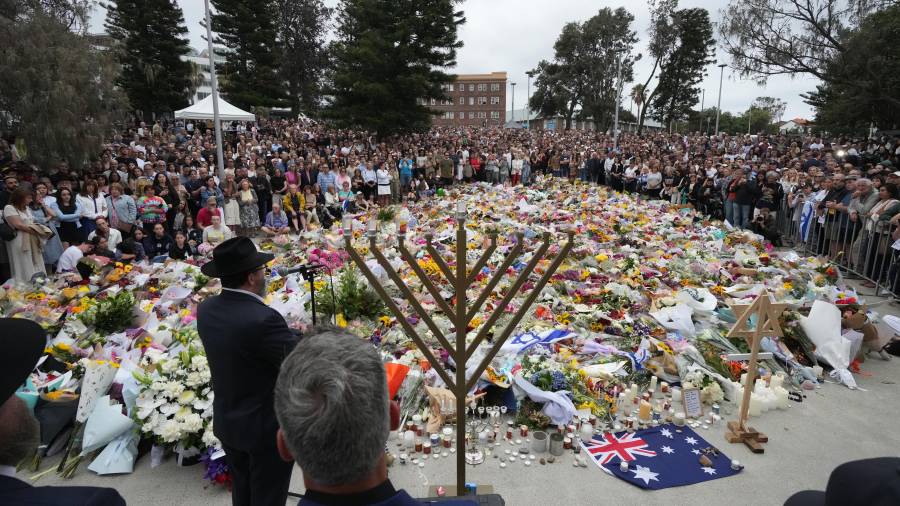 El rabino Motti Feldman, abajo a la izquierda, habla en una ceremonia de encendido de la menorá en un homenaje floral a las víctimas del tiroteo del domingo, en el Bondi Pavilion de Bondi Beach en Sídney.