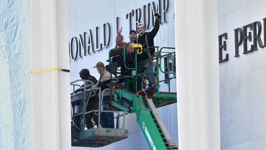 Trabajadores instalan la imagen de Donald Trump sobre la señalización actual en el Centro Kennedy en Washington.