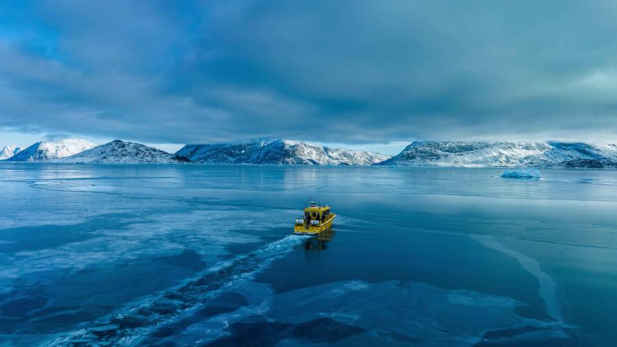 Un barco navega por una bahía con agua congelada a las afueras de Nuuk, Groenlandia.