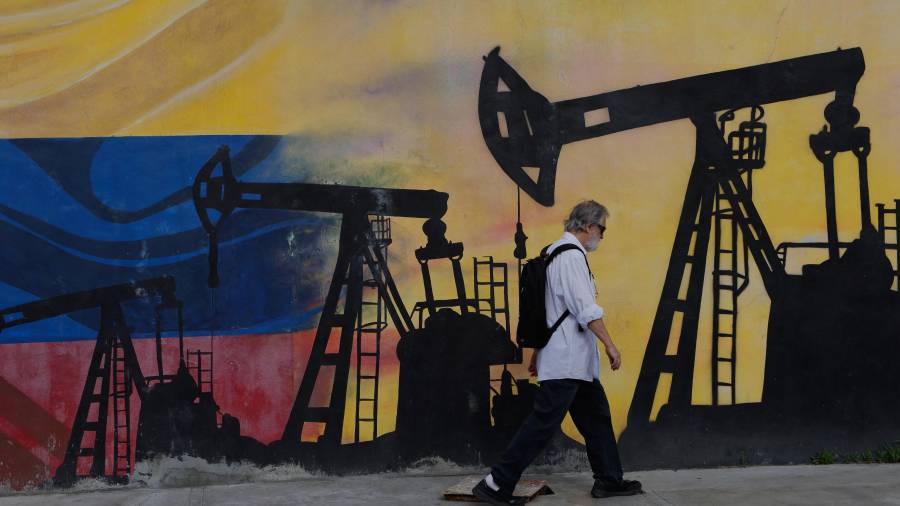 Un peatón pasa frente a un mural que muestra pozos petroleros en Caracas, un día después de que Donald Trump anunciara un acuerdo que otorga a EU una participación en las reservas de petróleo venezolano.