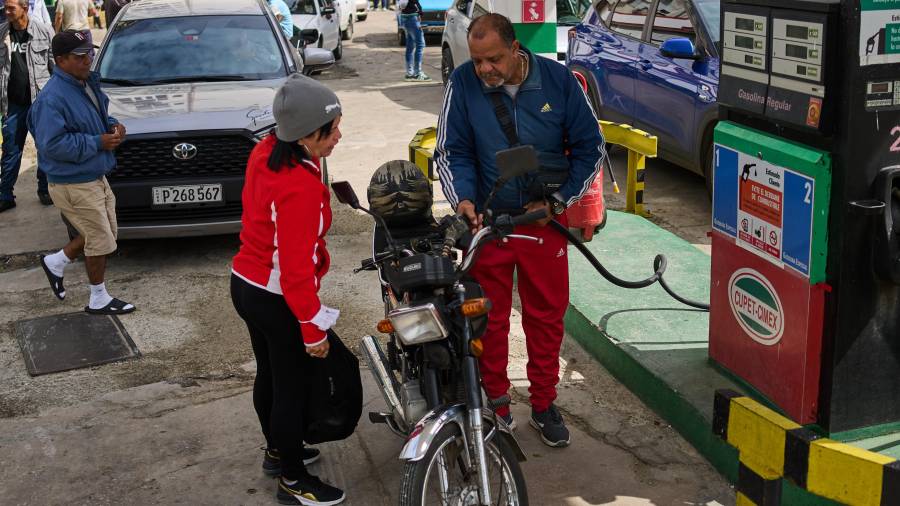 Un conductor reposta una motocicleta mientras otros conductores esperan en una larga fila en una gasolinera en La Habana, Cuba.