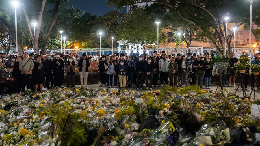 La gente ofrece flores a las víctimas cerca del lugar del incendio mortal del miércoles en Wang Fuk Court, una urbanización en el distrito de Tai Po, en los Nuevos Territorios de Hong Kong.