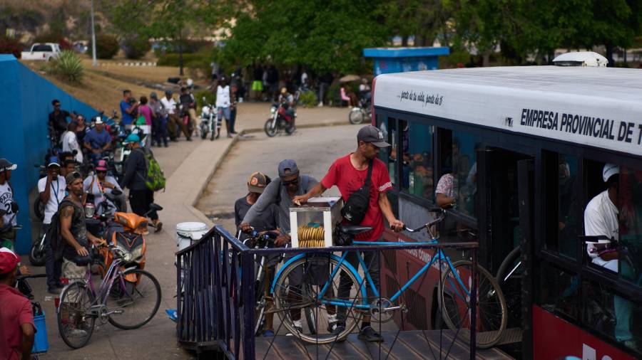Varias personas suben sus bicicletas a un autobús público para cruzar el Túnel de la Bahía en La Habana, en Cuba.