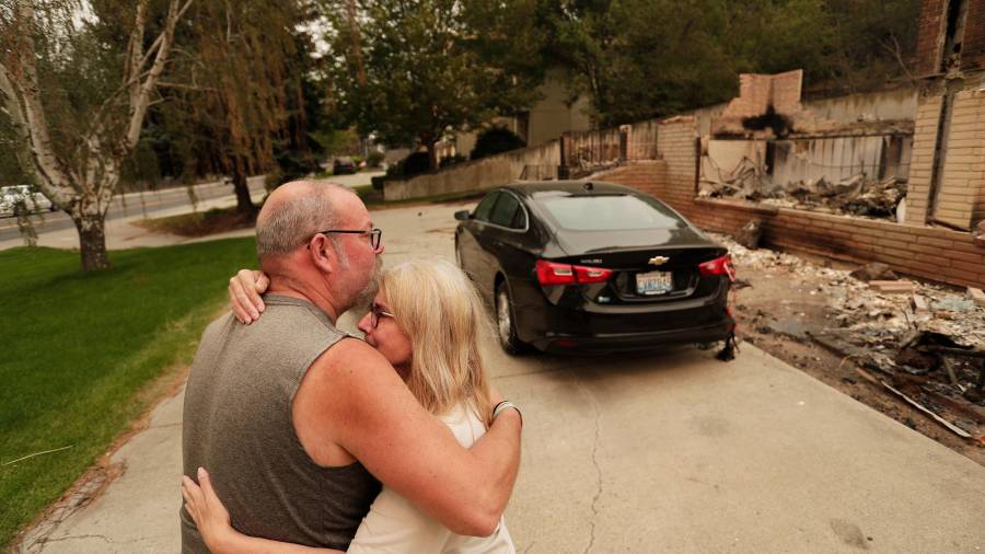 Allen Sather y su esposa Kimberley se abrazan ante la vivienda que arriendan en W. Indian Trail Road, que ardió en un incendio forestal en Spokane, Washington, el domingo 2 de agosto de 2026.