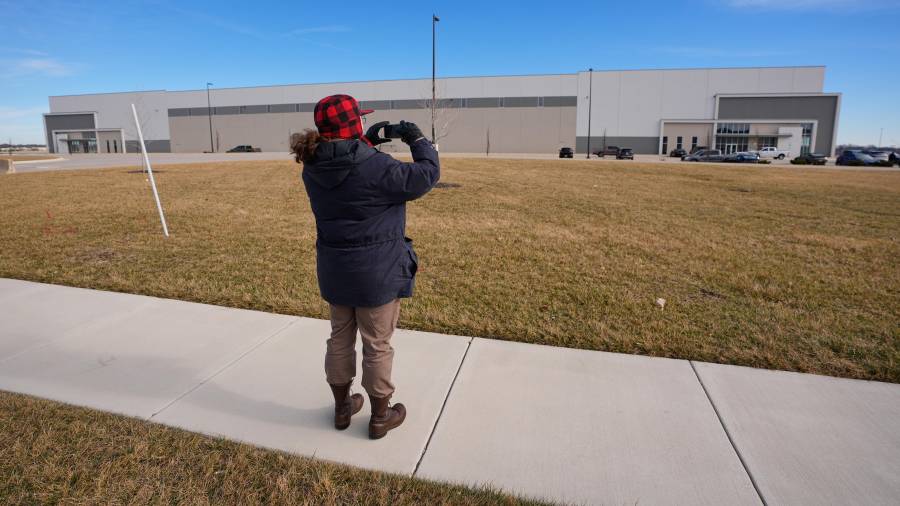 Un hombre toma fotos de un almacén mientras funcionarios federales recorren las instalaciones para considerar su reutilización como centro de detención del ICE en Belton, Missouri.