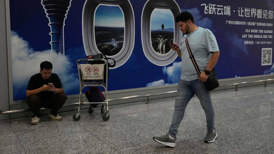 Un extranjero pasa junto a un cartel en el aeropuerto de Baiyun en Guangzhou, en la provincia sureña china de Guangdong.