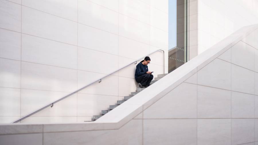 Una mujer revisa su teléfono sentada en una escalera afuera de un centro comercial en Beijing, China, el jueves 15 de enero de 2026.