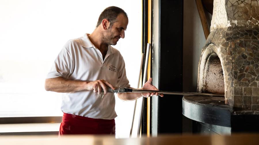 Davide prepara las pizzas en un horno tradicional, con leña.