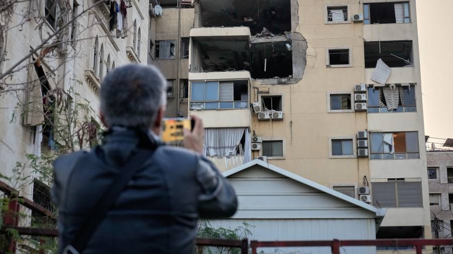 Un hombre toma fotos del daño en un edificio de apartamentos que fue impactado por un ataque aéreo israelí en Dahiyeh, un suburbio al sur de Beirut, Líbano.