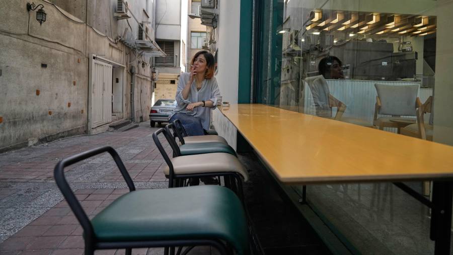 Una mujer fuma un cigarrillo en la terraza de un café en el centro de Teherán, Irán.