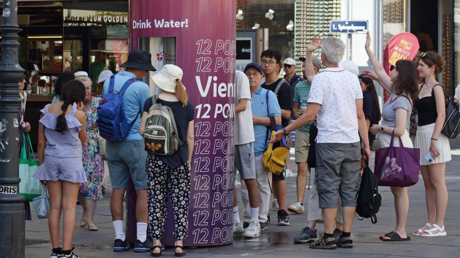 Varias personas forman una fila para rellenar botellas de agua en un caluroso día de verano en el centro de la ciudad de Viena, Austria.