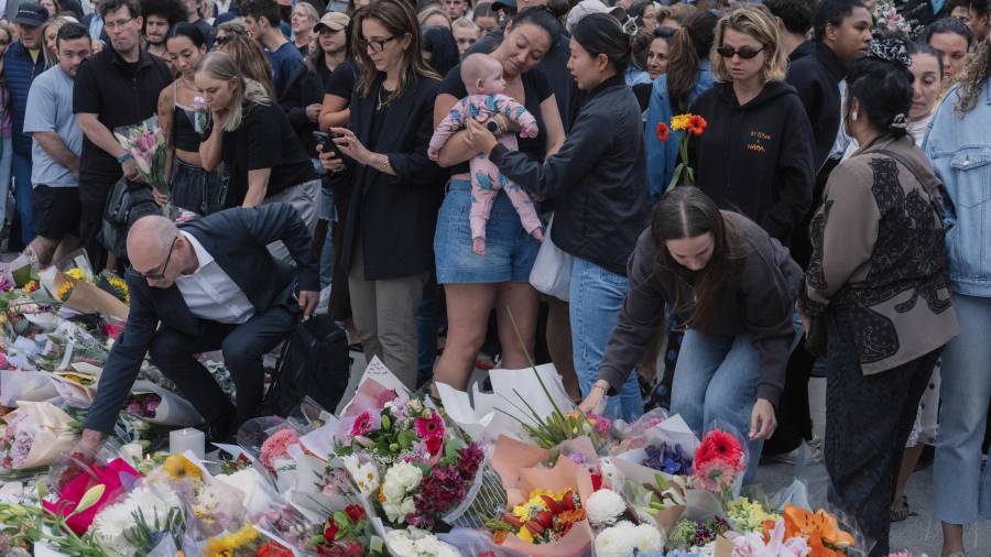 Personas depositan flores en un monumento improvisado en memoria de los fallecidos en el tiroteo mortal en Bondi Beach en Sídney, Australia.