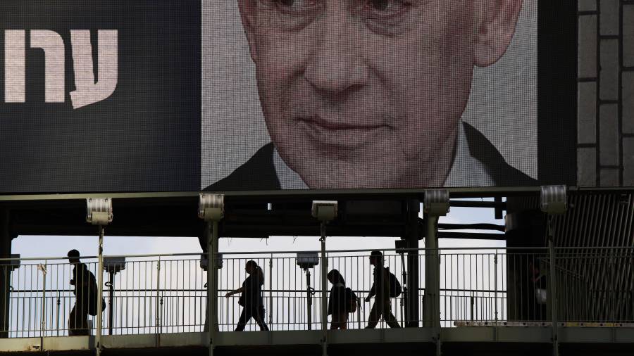Unas personas cruzan un puente bajo un anuncio de campaña televisiva en el que aparece el primer ministro israelí, Benjamin Netanyahu, de cara a las elecciones generales de Israel, en Ramat Gan, Israel.