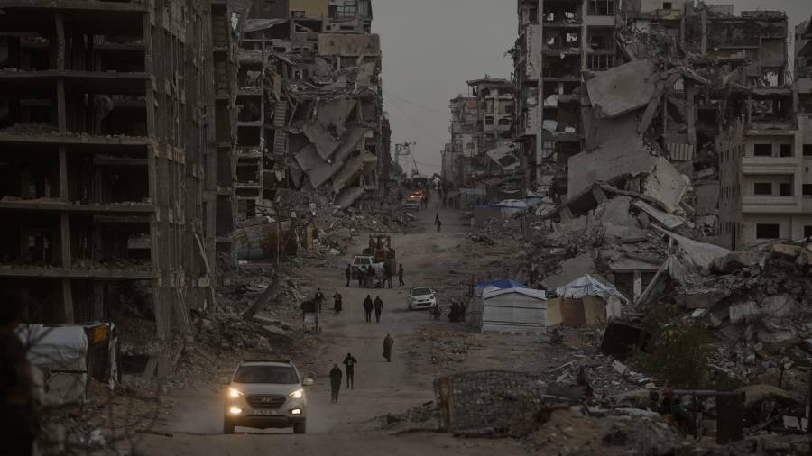 Palestinos caminan entre la destrucción en el barrio de Al-Karama, en la ciudad de Gaza.