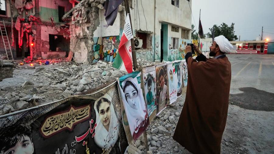 Un clérigo toma una foto en la destruida escuela Shajareh Tayyebeh, que se ha convertido en un lugar de duelo y recuerdo a los muertos en un ataque aéreo estadounidense el 8 de febrero en Minab, en el sur de Irán.