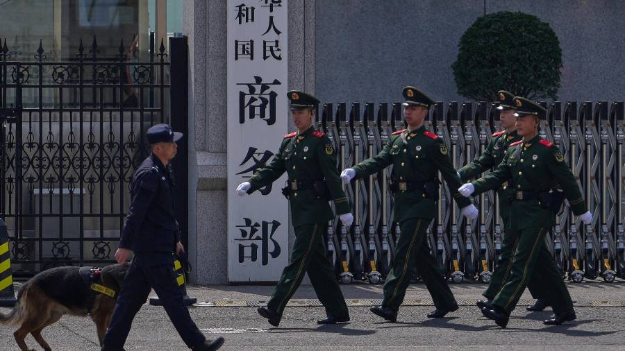 Soldados paramilitares y un policía con un perro rastreador pasan ante la puerta del Ministerio chino de Comercio, en Beijing, el 3 de abril de 2025.