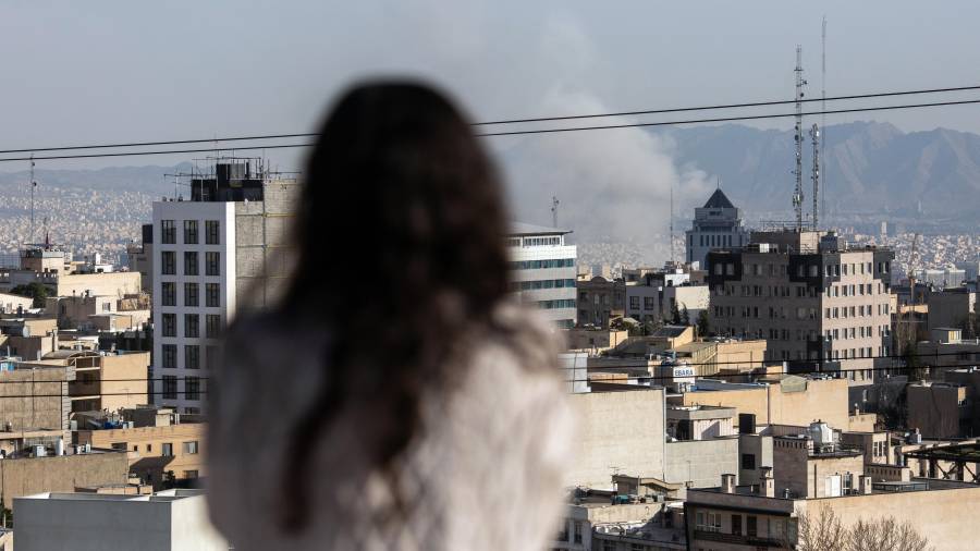 Una mujer observa cómo se eleva el humo tras un ataque con misiles en Teherán, Irán, el lunes 2 de marzo de 2026.