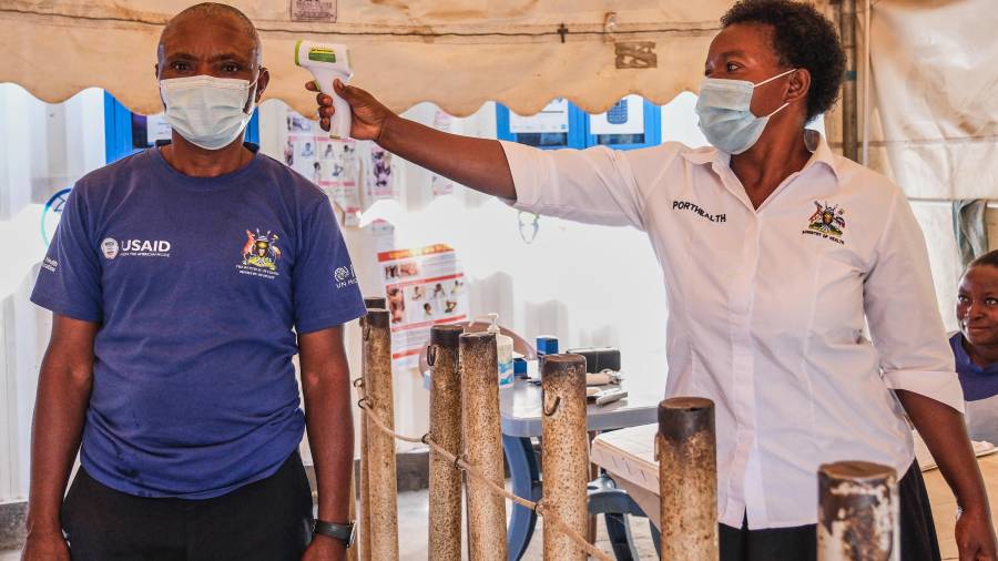 Una trabajadora de la salud revisa la temperatura de una persona en una clínica temporal en el cruce fronterizo de Mpondwe que conecta Uganda y la República Democrática del Congo, el 4 de junio de 2026.