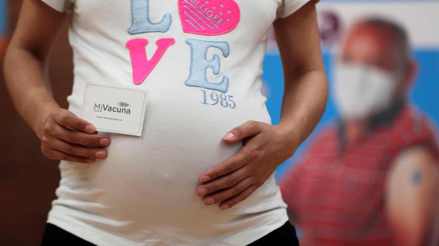 Una mujer embarazada muestra su carnet de vacunación luego de recibir la vacuna de Pfizer contra la covid-19 autorizada para madres gestantes, hoy, en el coliseo Cayetano Cañizares en Bogotá (Colombia).