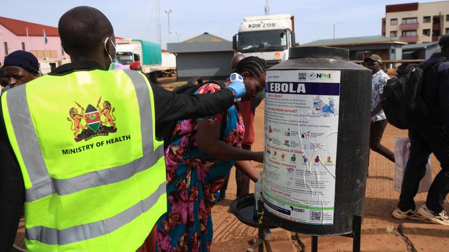 Varias personas se desinfectan las manos mientras un trabajador sanitario comprueba la temperatura de viajeros que cruzan de Uganda a Kenia, como parte de las medidas para contener la propagación del virus del ébola, en Busia, Kenia, el 15 de octubre de 2026.