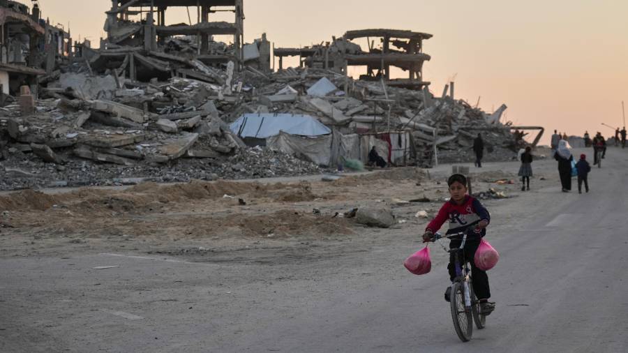 Un niño monta en bicicleta por una calle dañada en el campamento de Al-Shati en la ciudad de Gaza.
