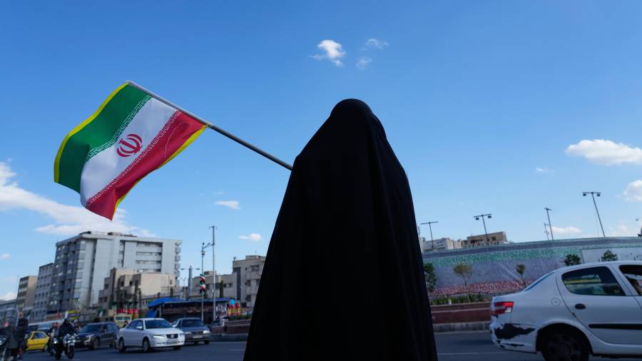 Una mujer ondea una bandera iraní durante una campaña en apoyo al gobierno en la plaza Enqelab-e-Eslami, o Revolución Islámica, en el centro de Teherán, Irán.