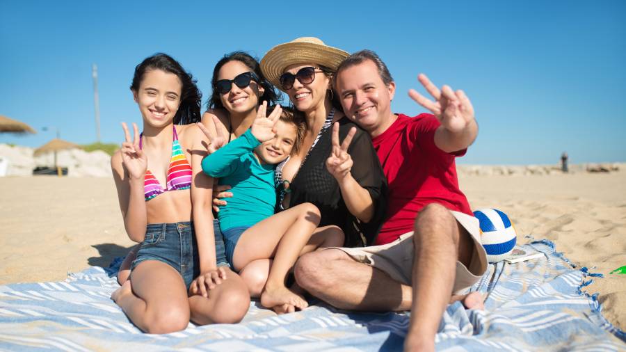 Portrait of smiling family at beach. Happy relatives looking at camera, showing victory sign. Family, vacation, outdoor activity concept