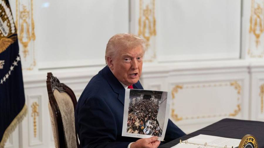 El presidente Donald Trump sostiene una fotografía mientras se dirige a reporteros tras hablar con las tropas por video desde su residencia de Mar-a-Lago en Palm Beach, Florida. FOTO: AP / Alex Brandon
